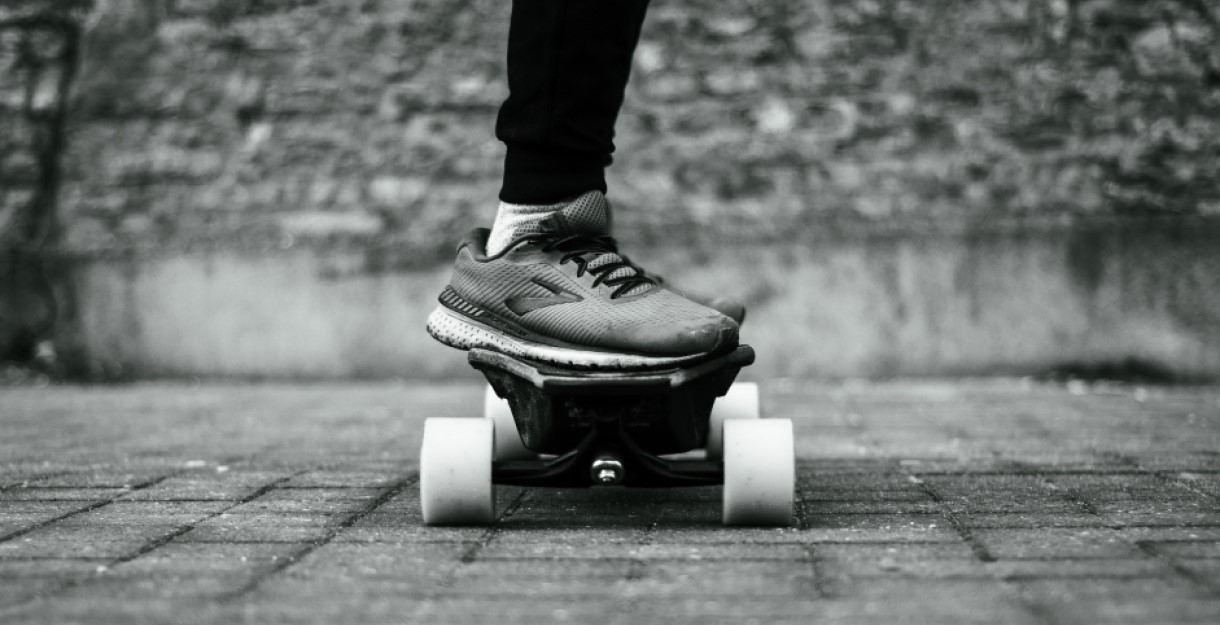 A close up, black and white, image of someone's feet on a skateboard