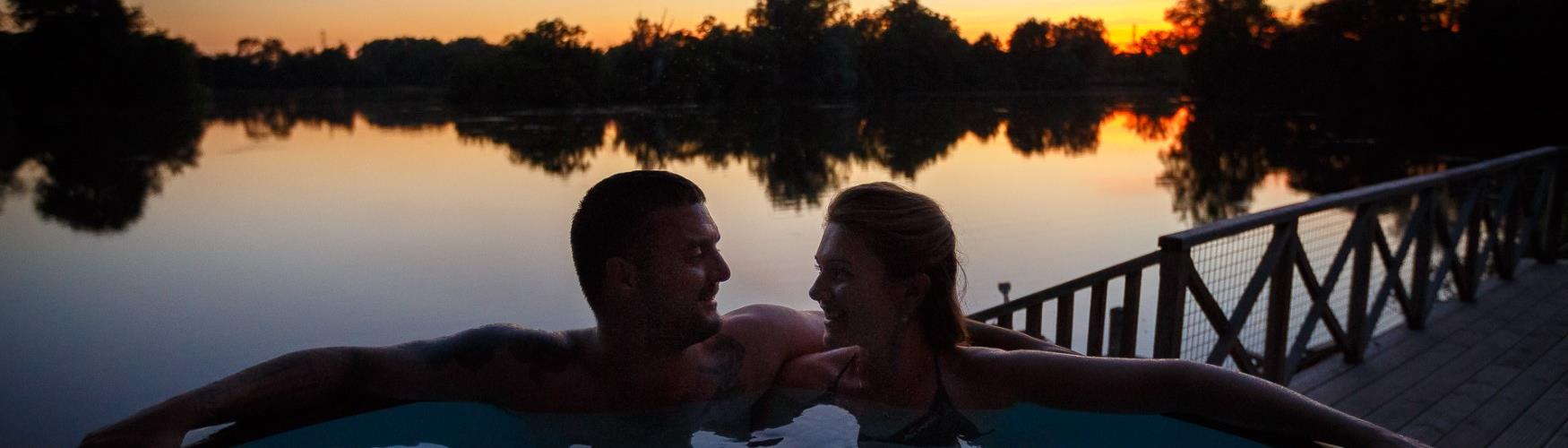Couple in an outdoor hot tub at Log House Holidays